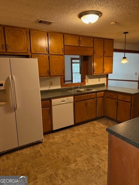 kitchen featuring white appliances, a textured ceiling, hanging light fixtures, and sink