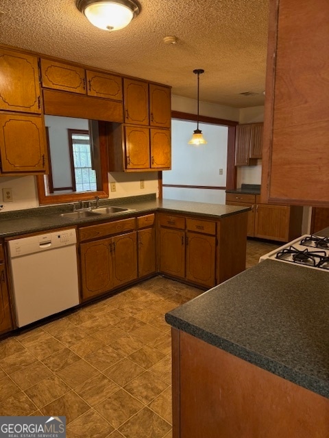 kitchen featuring kitchen peninsula, dishwasher, a textured ceiling, decorative light fixtures, and sink