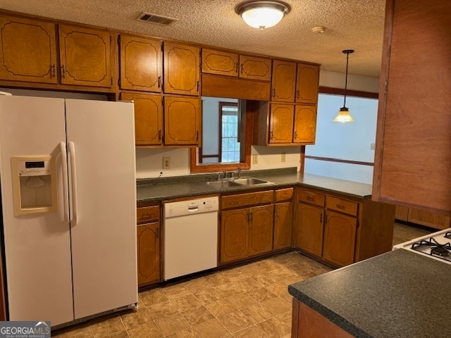 kitchen featuring a textured ceiling, hanging light fixtures, sink, and white appliances