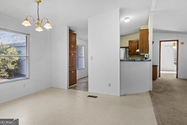 kitchen with white fridge, light colored carpet, decorative light fixtures, vaulted ceiling, and ceiling fan with notable chandelier