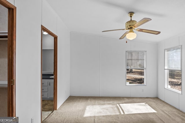 carpeted empty room with ceiling fan, crown molding, and lofted ceiling