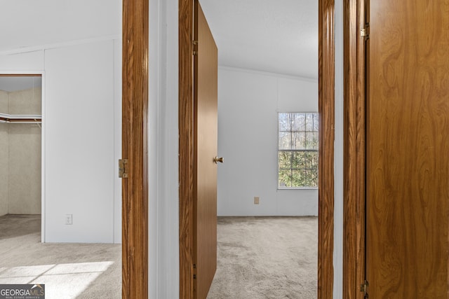 hallway featuring light carpet, a textured ceiling, vaulted ceiling, and ornamental molding