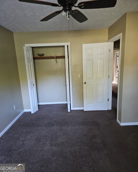 unfurnished bedroom featuring ceiling fan, a textured ceiling, a closet, and dark carpet