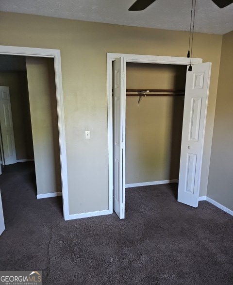 unfurnished bedroom with a textured ceiling and dark colored carpet