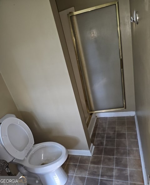 bathroom with a shower with door, tile patterned floors, and toilet