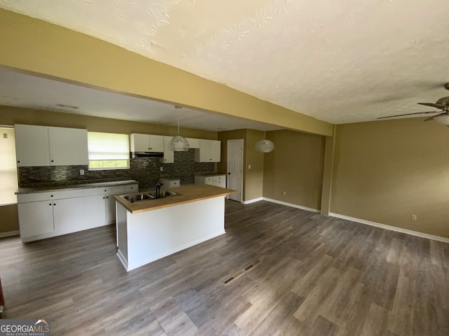 kitchen with hanging light fixtures, white cabinetry, ceiling fan, and dark wood-type flooring