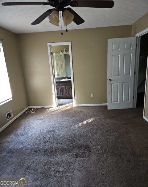 spare room with a textured ceiling, dark colored carpet, and ceiling fan