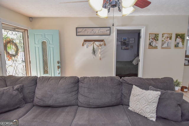 living room with a textured ceiling and ceiling fan