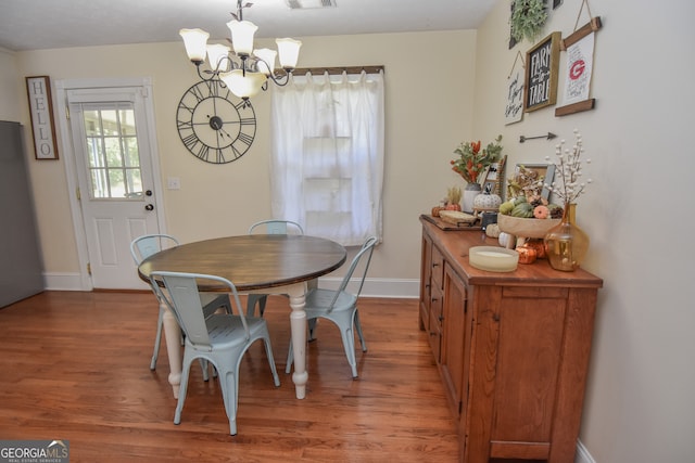 dining space featuring wood-type flooring and a notable chandelier