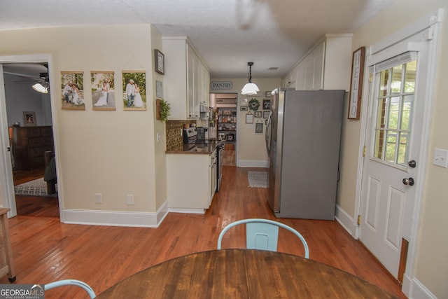 kitchen with pendant lighting, white cabinetry, light hardwood / wood-style floors, and appliances with stainless steel finishes