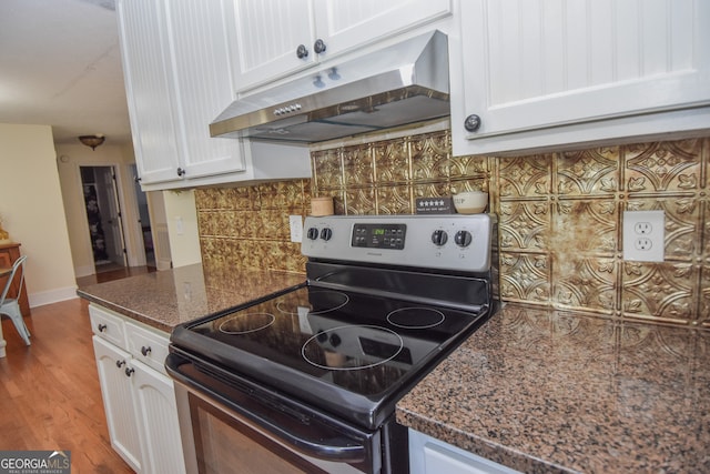 kitchen featuring electric range, white cabinets, light hardwood / wood-style flooring, backsplash, and dark stone countertops