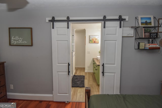 bedroom featuring wood-type flooring and a barn door