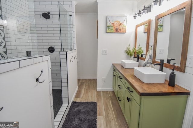 bathroom with a tile shower, vanity, and wood-type flooring