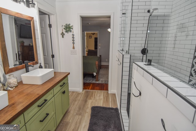 bathroom with wood-type flooring, vanity, and a tile shower