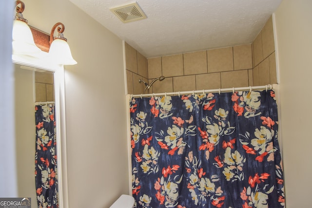 bathroom with a textured ceiling, toilet, and a shower with shower curtain