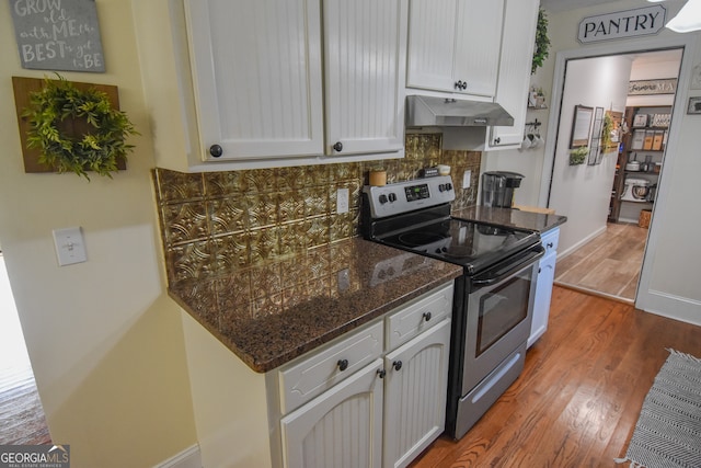 kitchen with wood-type flooring, stainless steel electric range oven, decorative backsplash, and white cabinetry