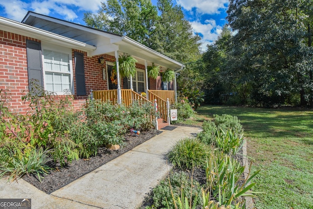 view of side of property featuring covered porch and a yard