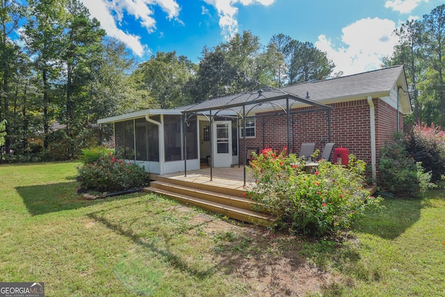 rear view of house with a lawn, a deck, and a sunroom