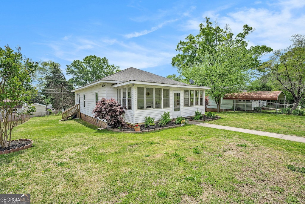 bungalow-style house featuring fence, a front lawn, and a sunroom