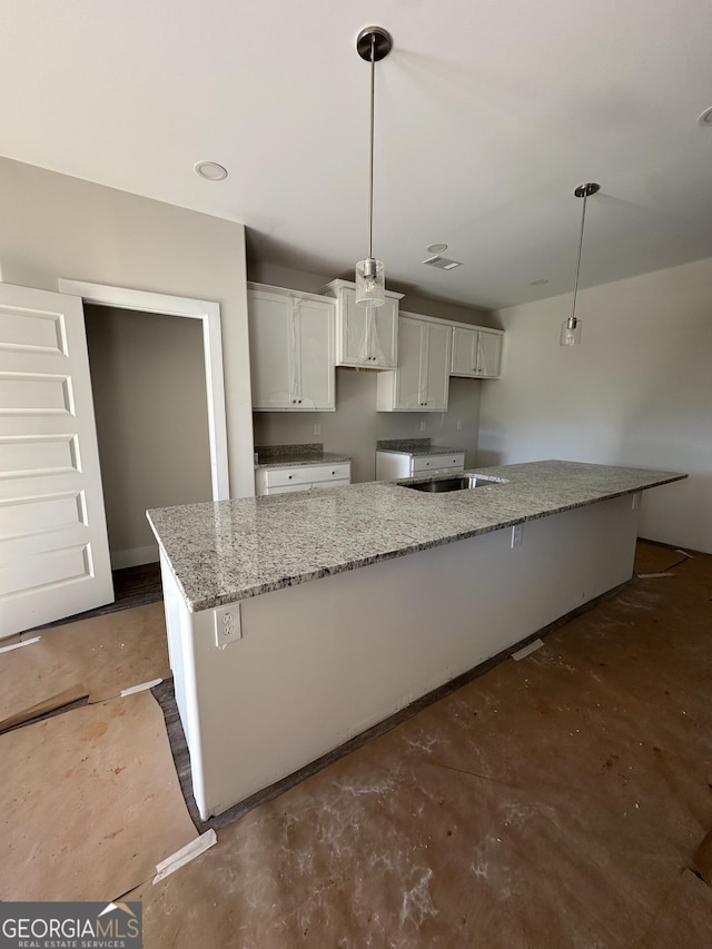 kitchen featuring a kitchen island, decorative light fixtures, sink, white cabinets, and light stone countertops