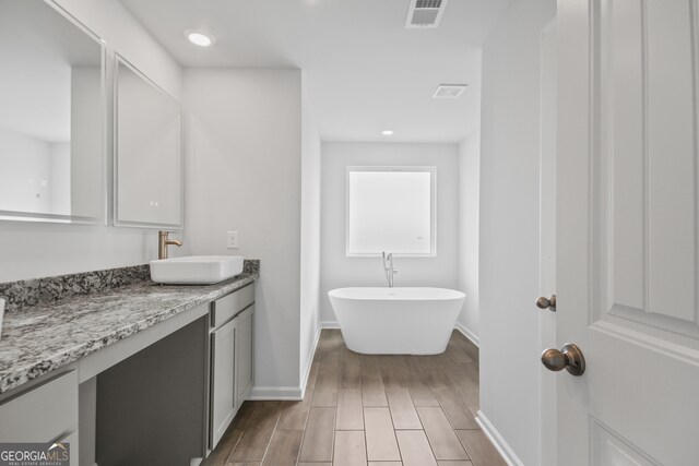 bathroom featuring vanity, a tub to relax in, and hardwood / wood-style floors