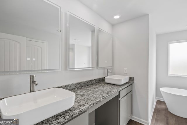 bathroom featuring vanity, hardwood / wood-style flooring, and a bathtub