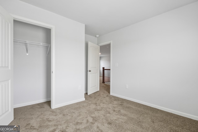 unfurnished bedroom with light carpet and a closet