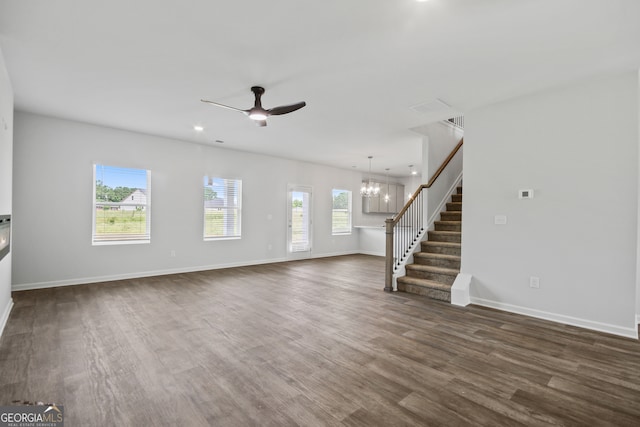 unfurnished living room featuring ceiling fan with notable chandelier and dark hardwood / wood-style floors