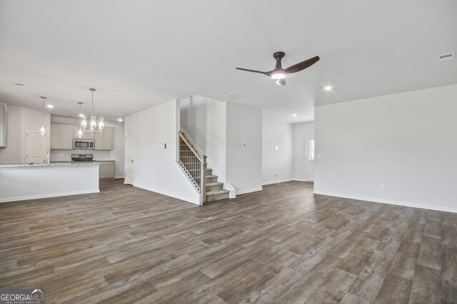 unfurnished living room with ceiling fan with notable chandelier and dark hardwood / wood-style flooring