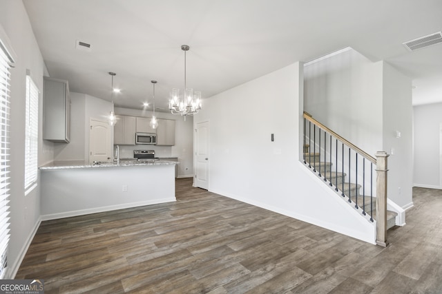 kitchen featuring gray cabinets, dark wood-type flooring, kitchen peninsula, hanging light fixtures, and stainless steel appliances