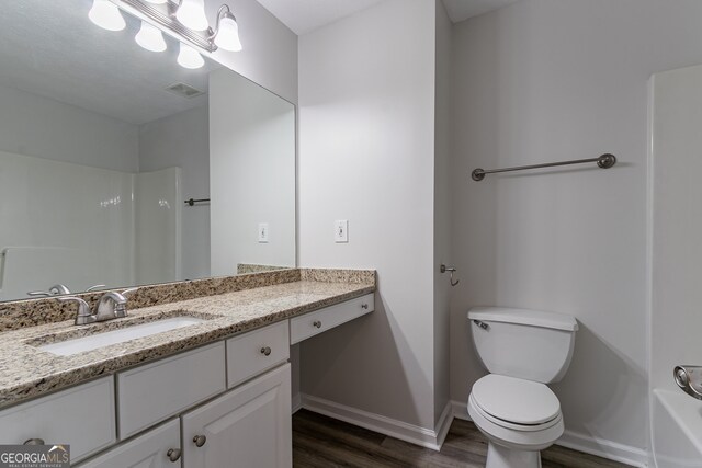 bathroom featuring vanity, hardwood / wood-style flooring, walk in shower, and toilet