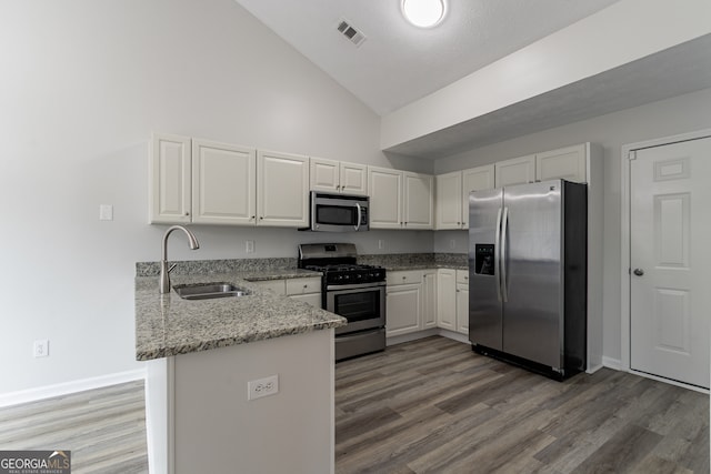 kitchen with white cabinets, sink, kitchen peninsula, high vaulted ceiling, and appliances with stainless steel finishes