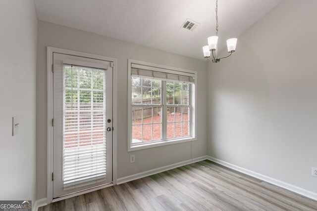 doorway with light hardwood / wood-style flooring and a notable chandelier