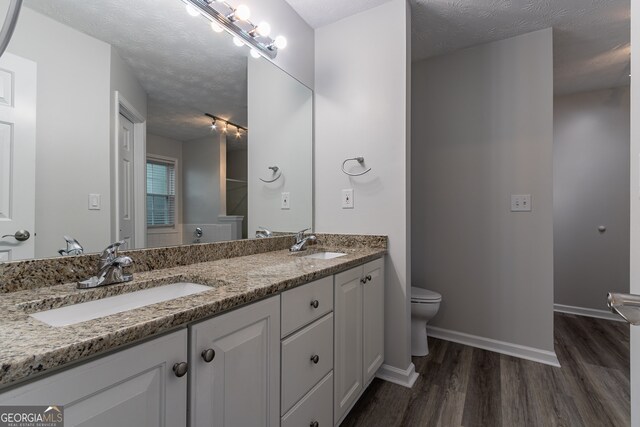 bathroom featuring vanity, hardwood / wood-style floors, toilet, and a textured ceiling