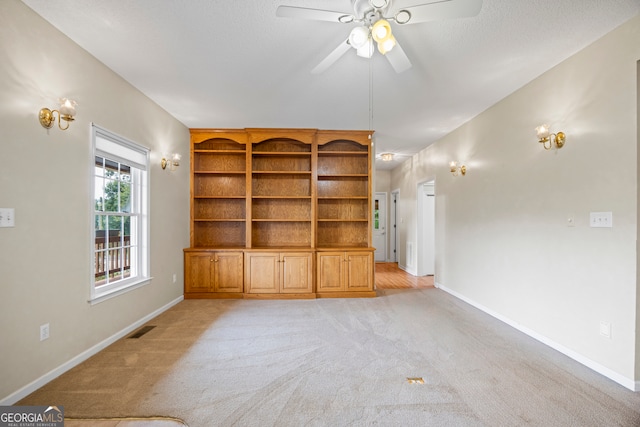 unfurnished living room featuring ceiling fan and light colored carpet