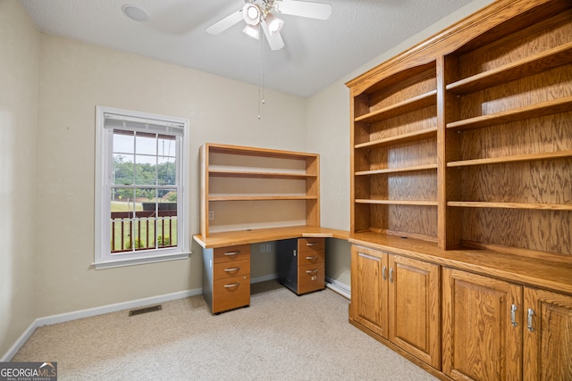 office space featuring light carpet, ceiling fan, and a textured ceiling