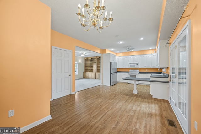 kitchen with hanging light fixtures, white appliances, light hardwood / wood-style flooring, white cabinetry, and ceiling fan with notable chandelier