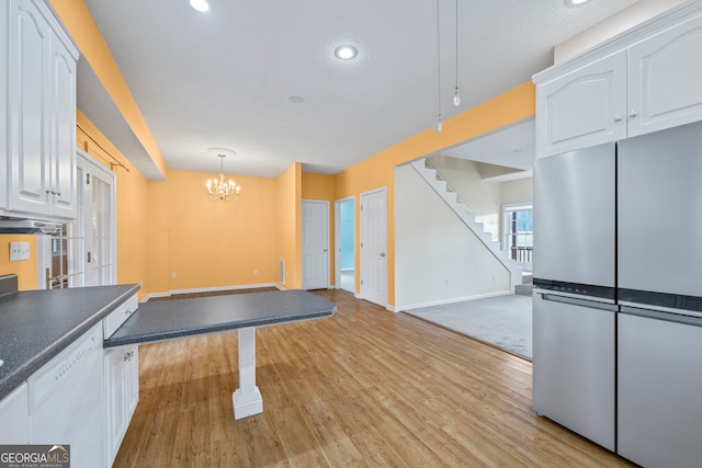 interior space featuring light wood-type flooring, a notable chandelier, white cabinets, hanging light fixtures, and stainless steel fridge