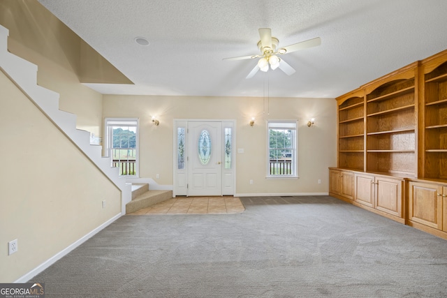 foyer entrance featuring ceiling fan, light colored carpet, and plenty of natural light