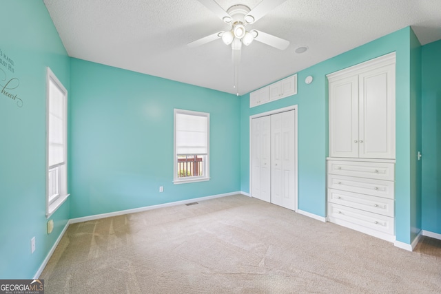 unfurnished bedroom with a closet, ceiling fan, carpet floors, and a textured ceiling