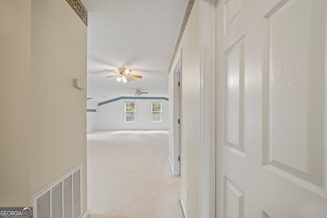 hall featuring a textured ceiling and light colored carpet