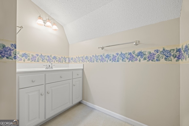 bathroom with vanity, lofted ceiling, and a textured ceiling