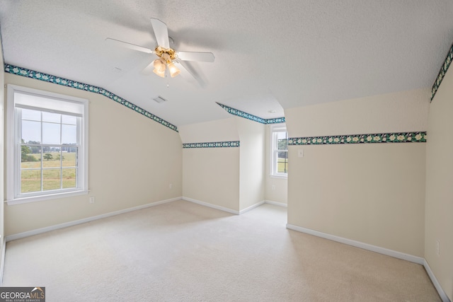 bonus room with lofted ceiling, ceiling fan, light colored carpet, and a textured ceiling