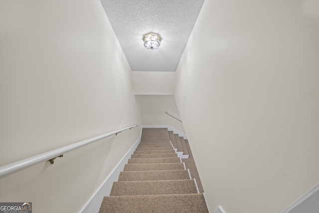 stairs featuring a textured ceiling and carpet