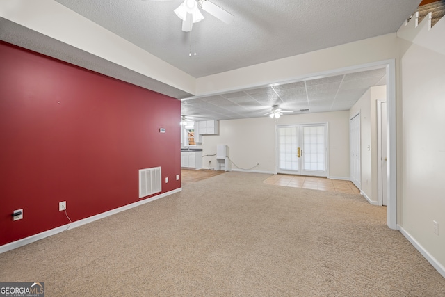 unfurnished living room with french doors, light colored carpet, a textured ceiling, and ceiling fan