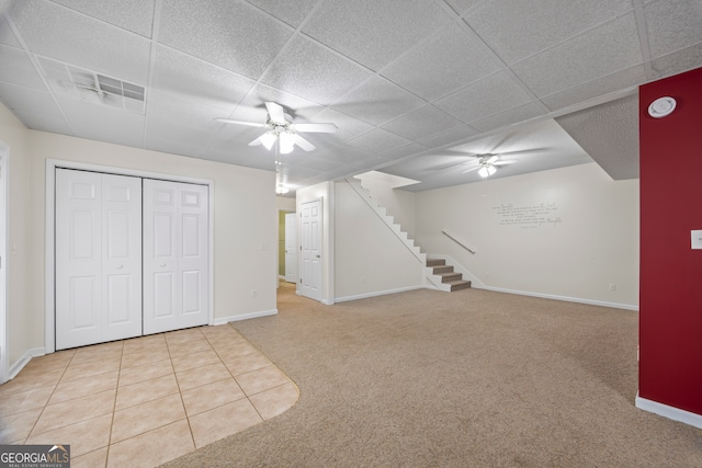 basement featuring ceiling fan, light colored carpet, and a paneled ceiling