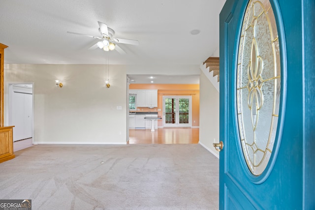 carpeted foyer entrance with a textured ceiling and ceiling fan