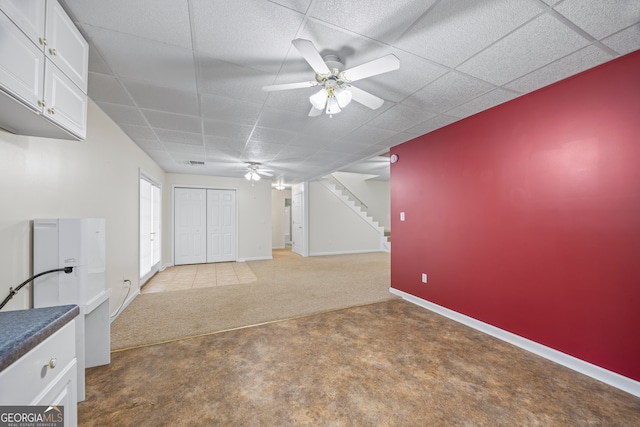 basement with carpet flooring, ceiling fan, and a drop ceiling