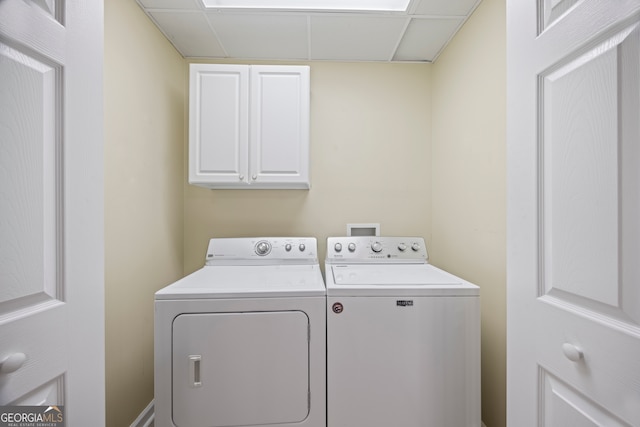 clothes washing area with cabinets and washer and dryer