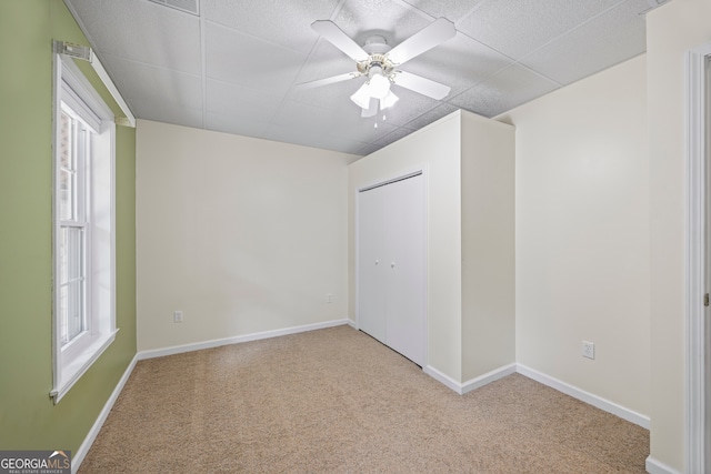 carpeted spare room featuring ceiling fan and plenty of natural light